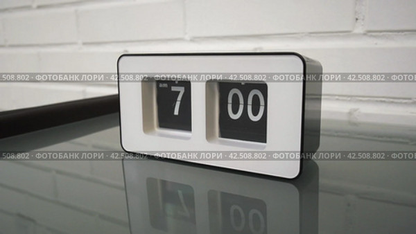 Перекидной циферблат часов будильника. Монтаж двух планов. Flip clock mechanism. 7:00 AM. Flip clock watch face. White brick wall in the background. Slow motion 240 fps. Стоковое видео, видеограф EStarodubov / Фотобанк Лори
