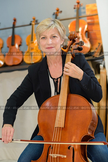photo of female musician playing a cello in instrument store. Стоковое фото, агентство Ingram Publishing / Фотобанк Лори
