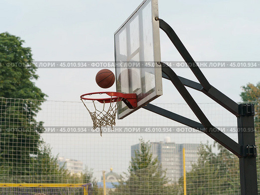 Photography of sports competitions on the sports ground in the Gorky park. Basketball basket and ball falling into it in summer day. Healthy lifestyles of youth. Стоковое фото, фотограф YuryKara / Фотобанк Лори