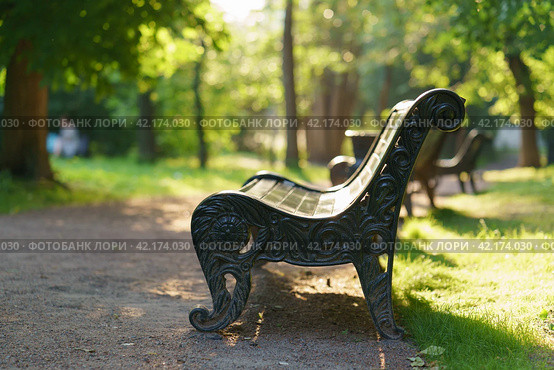 Photography of the green public city park. Sunny summer day. Natural background. Silhouette of man on distance. Empy bench. Resting of nature. Free space for message. Стоковое фото, фотограф YuryKara / Фотобанк Лори