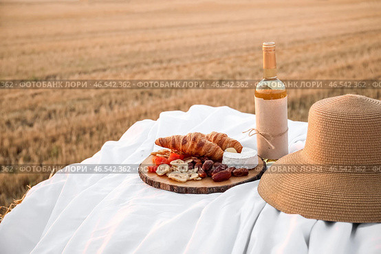 Пикник с вкусной закуской и вином на стоге сена на убранном поле. Стоковое фото, фотограф Pixel_shot / Фотобанк Лори