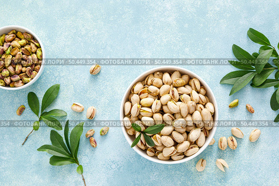 Pistachios. Whole pistachios with green leaves and pistachio nut kernels. Healthy natural vegetarian organic food. Top view, copy space. Стоковое фото, агентство Ingram Publishing / Фотобанк Лори