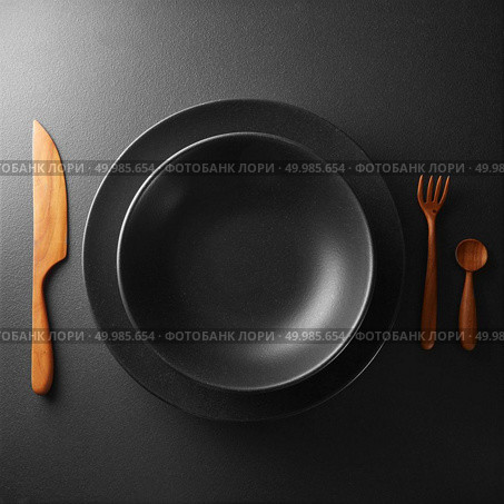 plate and cutlery on a black table . Food concept. plate and cutlery on a black table. Стоковое фото, агентство Ingram Publishing / Фотобанк Лори