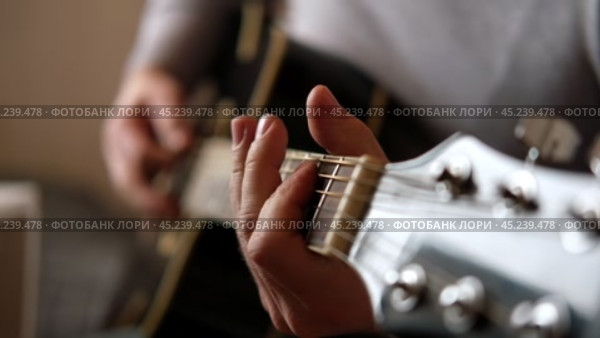 Playing the guitar. Strumming black acoustic guitar. Musician plays music. Man fingers holding mediator. Male hand playing guitar neck in dark room. Unrecognizable person rehearsing, fretboard closeup. Стоковое видео, видеограф Марина Демидюк / Фотобанк Лори