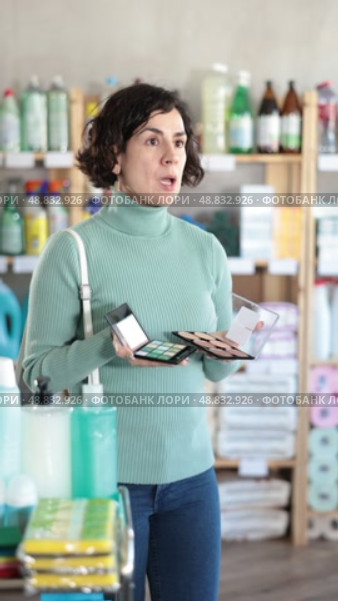 Pleased middle-aged woman deciding which makeup items to buy in retail store. Стоковое видео, видеограф Яков Филимонов / Фотобанк Лори