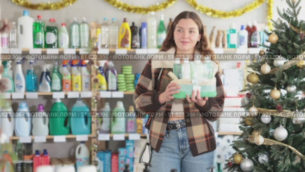 Pleased young woman deciding which gift basket to buy in hygiene products shop in X-mas. Стоковое видео, видеограф Яков Филимонов / Фотобанк Лори
