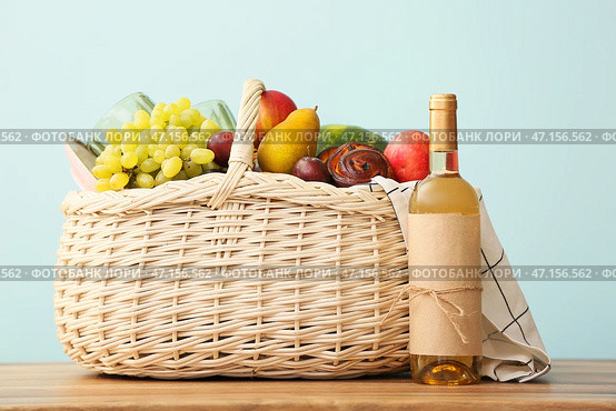 Плетеная корзина с вкусной едой и вином для пикника на столе на цветном фоне. Стоковое фото, фотограф Pixel_shot / Фотобанк Лори