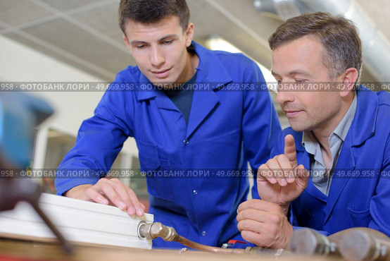 Plumber and appretice with radiator on workbench. Стоковое фото, агентство Ingram Publishing / Фотобанк Лори