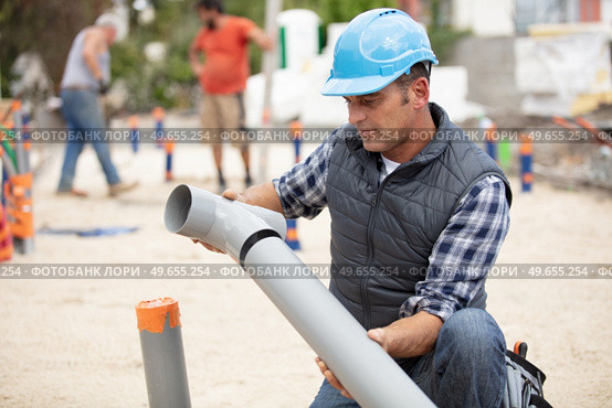 plumber assembling pvc sewage pipes in house foundation. Стоковое фото, агентство Ingram Publishing / Фотобанк Лори