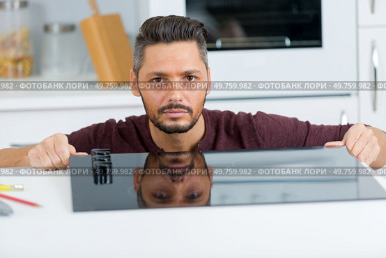 plumber crouching and taking notes in the kitchen. Стоковое фото, агентство Ingram Publishing / Фотобанк Лори
