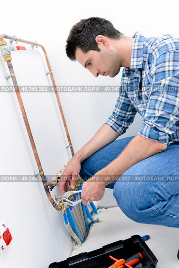 Plumber making adjustments to the heating system. Стоковое фото, агентство Ingram Publishing / Фотобанк Лори