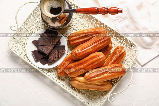 Поднос с вкусными эклерами, шоколадом и джезвой кофе на светлом фоне. Стоковое фото, фотограф Pixel_shot / Фотобанк Лори