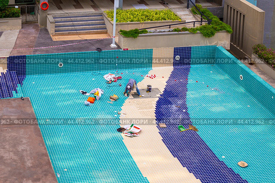 Pool repair. Workers lay new tiles on the bottom of the pool, Thailand, Pattaya (2024 год). Редакционное фото, фотограф Коханова Наталья / Фотобанк Лори