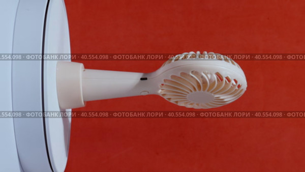 Portable fan on a stand. Rotates on the subject table. On a coral background. Стоковое видео, видеограф Vadzim Yakubovich / Фотобанк Лори