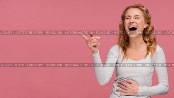 portrait female laughs pointing copy space. Стоковое фото, агентство Ingram Publishing / Фотобанк Лори