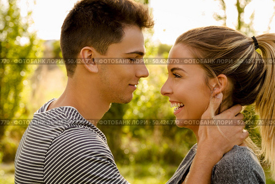 Portrait of a happy young couple in love and giving a kiss. Стоковое фото, агентство Ingram Publishing / Фотобанк Лори