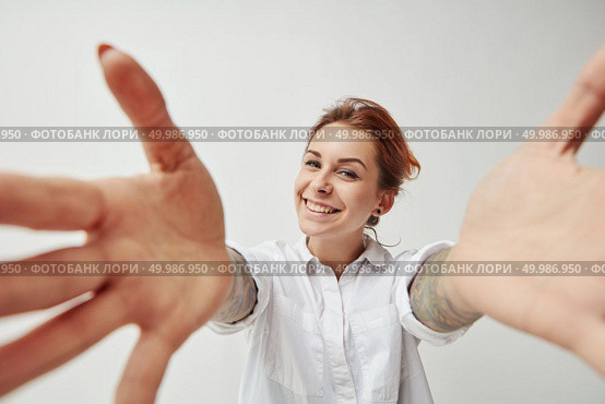 Portrait of a happy young girl with outstretched open hands to embrace. Joyful greeting. Young woman smiling with her arms open on white background. Стоковое фото, агентство Ingram Publishing / Фотобанк Лори