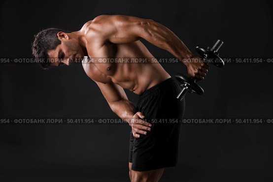 Portrait of a muscular man lifting weights against a dark background. Стоковое фото, агентство Ingram Publishing / Фотобанк Лори