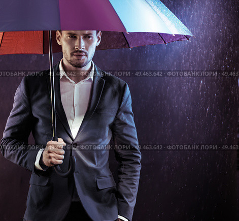 Portrait of a serious, calm businessman holding a colorful umbrella. Стоковое фото, агентство Ingram Publishing / Фотобанк Лори
