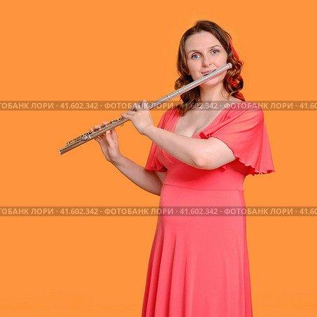Portrait of a woman musician with a flute on a studio yellow background. Flutist with a large concert transverse flute in her hands. Стоковое фото, фотограф Андрей Журавлев / Фотобанк Лори