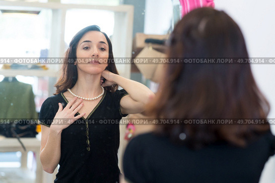 portrait of a woman trying on necklace. Стоковое фото, агентство Ingram Publishing / Фотобанк Лори