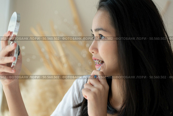 Portrait of a young asian woman with braces on her teeth. Стоковое фото, агентство Ingram Publishing / Фотобанк Лори