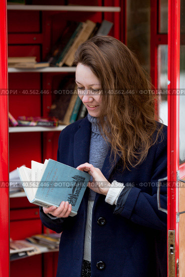 Portrait of a young woman over 30 years old with a book in her hands, a girl took a book from a street library. Modern lifestyle, reading books and education. Стоковое фото, фотограф Photojuli / Фотобанк Лори