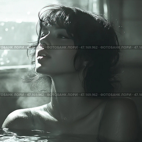 Portrait of a young woman with short wavy hair, standing in water. She appears thoughtful, her face turned upwards as if she is catching the light or steam. Drops of water glisten on her skin, creating an effect of wetness and intimacy of the scene. The photograph is made in soft, muted tones, close to black and white or sepia. The atmosphere of the picture is mysterious, with an emphasis on natural beauty, the play of light and shadow. The water and light steam give the scene a sense of coziness and calm, perhaps creating associations with a bath or a hot spring. Стоковое AI-изображение, AI-художник Анна Кривицкая / Фотобанк Лори