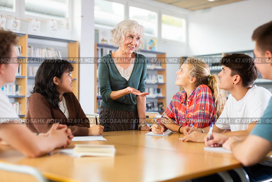 Portrait of adult female librarian and diligent schoolkids during classes in library. Стоковое фото, фотограф Яков Филимонов / Фотобанк Лори