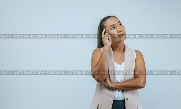 Portrait of Asian woman wearing casual clothes pointing with a finger at the head and looking away at empty space aside, isolated over background in studio. Стоковое фото, агентство Ingram Publishing / Фотобанк Лори