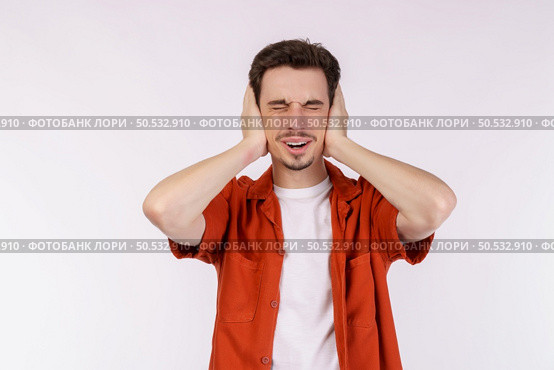 Portrait of attractive man close ears from noisy neighbours, looking up and shouting annoyed, hearing loud music on isolated background. . Стоковое фото, агентство Ingram Publishing / Фотобанк Лори