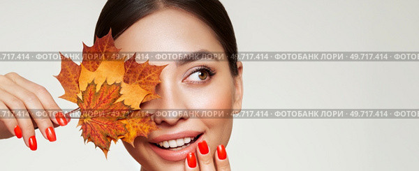 Portrait of beautiful young woman with autumn leafs. Healthy clean fresh skin natural make up beauty eyes and red nails. Стоковое фото, агентство Ingram Publishing / Фотобанк Лори