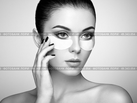 Portrait of Beauty Woman with eye Patches showing an effect of Perfect Skin. Beautiful Face of young Woman with clean Fresh Skin and bare shoulders on beige background. Brunette Spa Girl. Стоковое фото, агентство Ingram Publishing / Фотобанк Лори