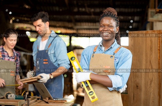 Portrait of carpenter female worker standing in front of colleague in workshop. Стоковое фото, агентство Ingram Publishing / Фотобанк Лори