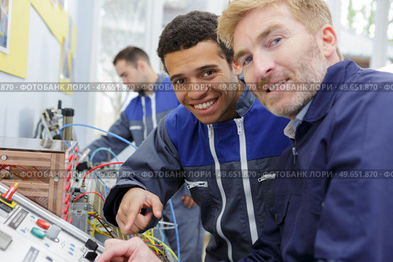 portrait of engineer and apprentice by machinery controls. Стоковое фото, агентство Ingram Publishing / Фотобанк Лори