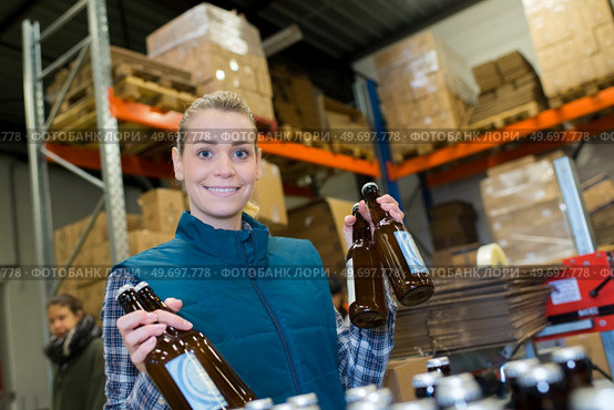 portrait of female worker holding bottles of beer. Стоковое фото, агентство Ingram Publishing / Фотобанк Лори