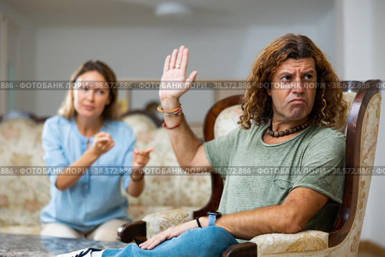 Portrait of frustrated man in room, while disgruntled wife scolds his. Стоковое фото, фотограф Яков Филимонов / Фотобанк Лори