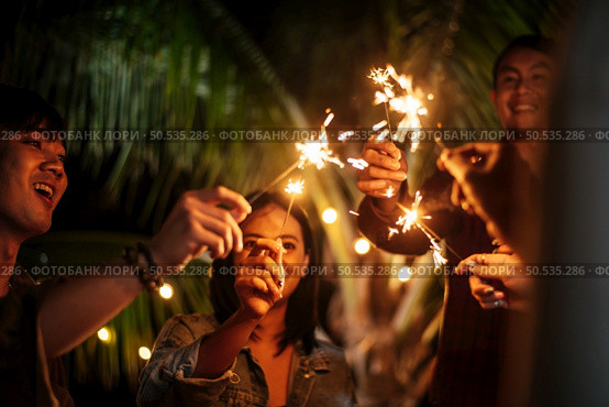 Portrait of Happy Asian group of friends having fun with sparklers outdoor - Young people having fun with fireworks at night time  - People, food, drink lifestyle, new year celebration concept. Стоковое фото, агентство Ingram Publishing / Фотобанк Лори