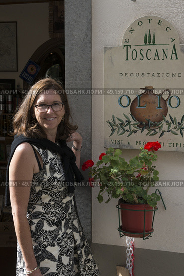 Portrait of happy woman standing in front of shop, Radda in Chianti, Tuscany, Italy. Стоковое фото, агентство Ingram Publishing / Фотобанк Лори