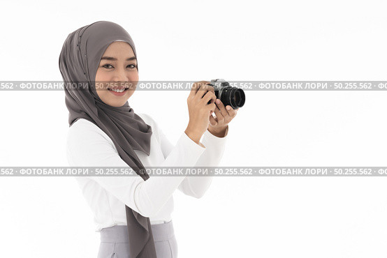Portrait of happy young adult asian muslim fenale tourist and photographer holding a camera and smiling. Studio shot of woman isolated on white background. Стоковое фото, агентство Ingram Publishing / Фотобанк Лори