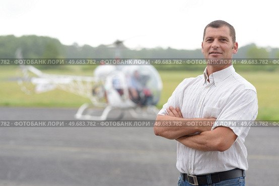 portrait of man at airfield helicopter in background. Стоковое фото, агентство Ingram Publishing / Фотобанк Лори