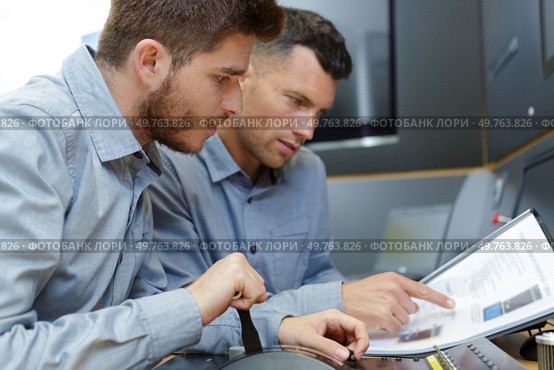 portrait of men looking at handbook. Стоковое фото, агентство Ingram Publishing / Фотобанк Лори