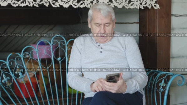 Portrait of senior man using mobile phone, holding device, texting, surfing internet. Old male looking at web camera, talking online. Elderly person chatting. Modern technologies and older generation. Стоковое видео, видеограф Марина Демидюк / Фотобанк Лори