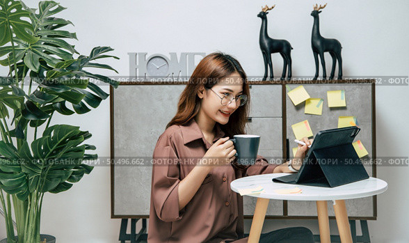 Portrait of smiling happy woman relaxing with coffee, using technology of digital pen on tablet to working from home during self-isolation and quarantine covid-19 coronavirus outbreak. Стоковое фото, агентство Ingram Publishing / Фотобанк Лори
