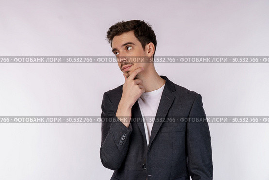 Portrait of young businessman thinking touching chin isolated over white background. Thinking worried about a question, concerned and nervous with hand on chin. Стоковое фото, агентство Ingram Publishing / Фотобанк Лори