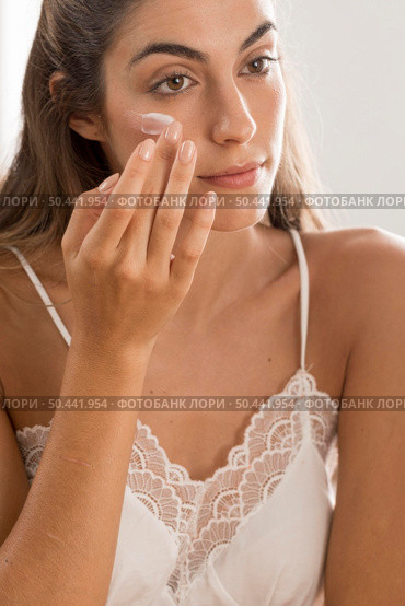 portrait woman applying cream her face. Стоковое фото, агентство Ingram Publishing / Фотобанк Лори