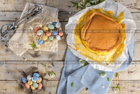 Portuguese sponge cake wrapped in the typical paper used on the baking, on wooden background with painted easter eggs decoration. Стоковое фото, агентство Ingram Publishing / Фотобанк Лори