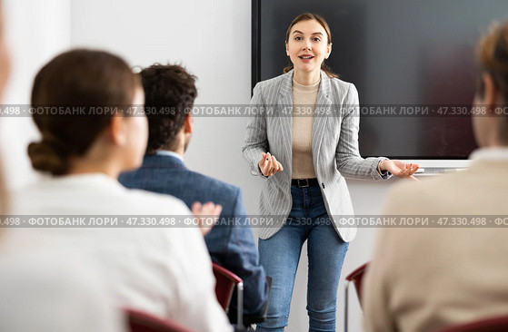 Positive skilled female coach explaining topic to group of people during foreign language class in auditory. Стоковое фото, фотограф Яков Филимонов / Фотобанк Лори