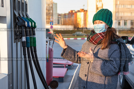 Positive woman choosing her type of gasoline, driver wearing safety mask on urban petrol station. Стоковое фото, фотограф Кекяляйнен Андрей / Фотобанк Лори