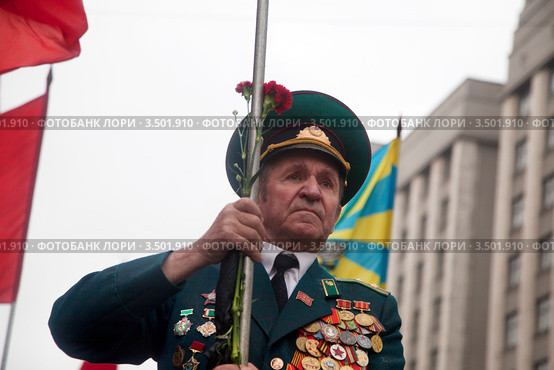 Постоянный знаменосец КПРФ несет Знамя Победы во главе колонны на демонстрации, посвященной Дню Победы, Москва (2012 год). Редакционное фото, фотограф Николай Винокуров / Фотобанк Лори